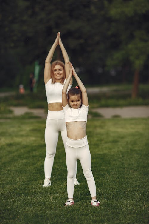 Free A Woman Doing the Upward Tree Pose with her Daughter Stock Photo