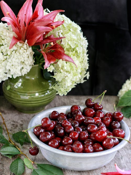 A Bowl of Cherries beside a Flower Vase