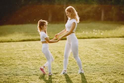 A Woman Holding Hands with her Daughter at a Park
