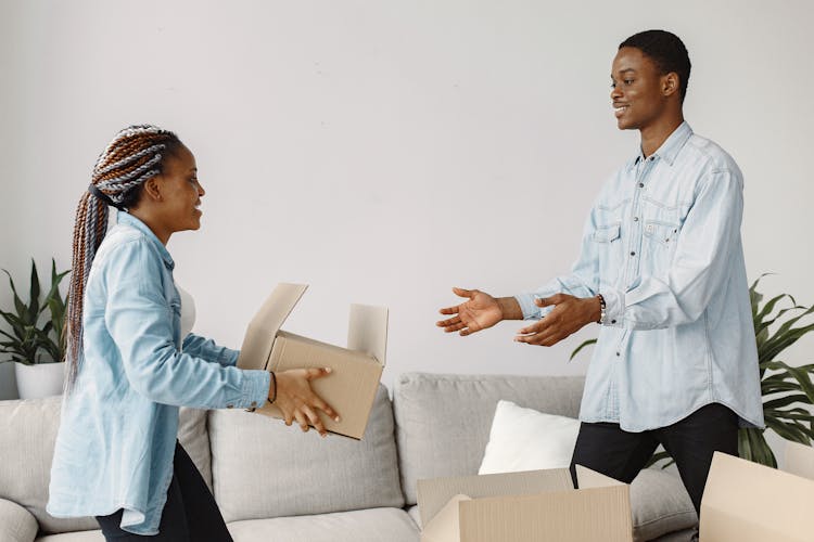 A Woman Handing A Cardboard Box To A Man