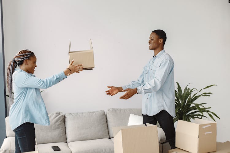 A Woman Handing A Cardboard Box To A Man