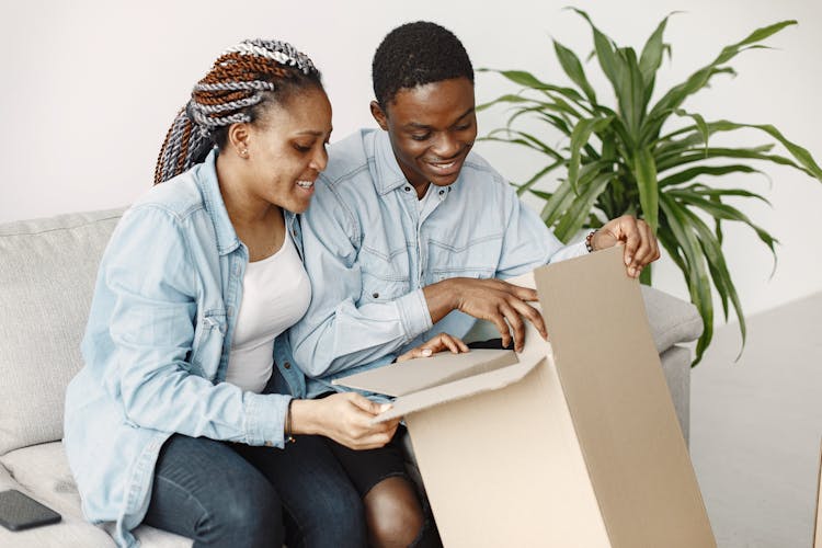 A Couple Opening A Cardboard Box Together