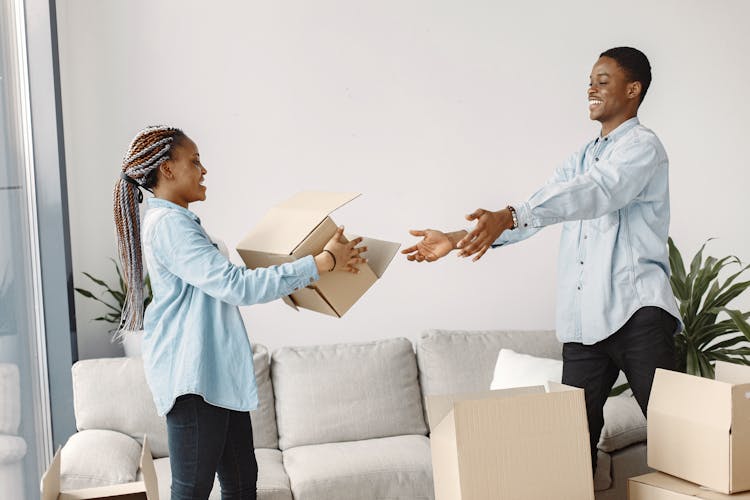 A Woman Handing A Cardboard Box To A Man