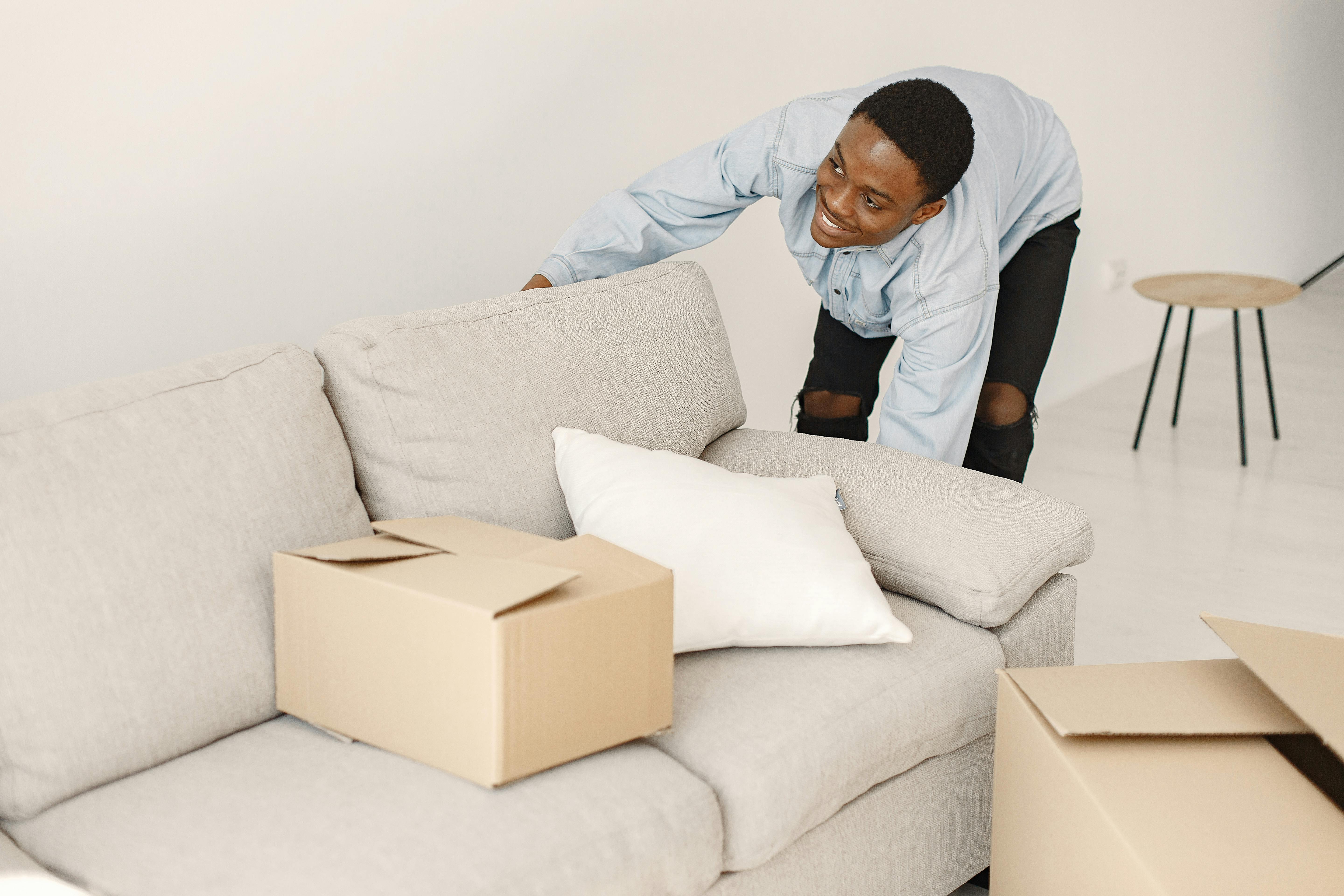 A Young Man Picking up a Couch · Free Stock Photo
