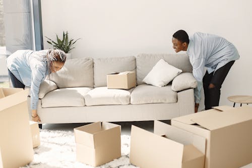 Free A Man and a Woman Lifting a Couch Together Stock Photo