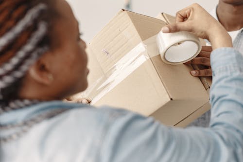 Free A Person Putting Tape on a Cardboard Box Stock Photo