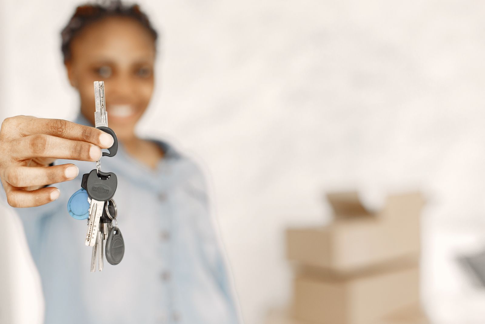 Free Close-up of a woman holding keys with a blurred background, symbolizing a new home or real estate concept. Stock Photo