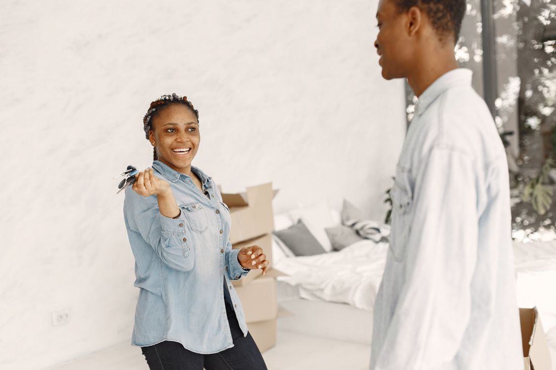 Casal sorrindo segurando as chaves de um apartamento novo.