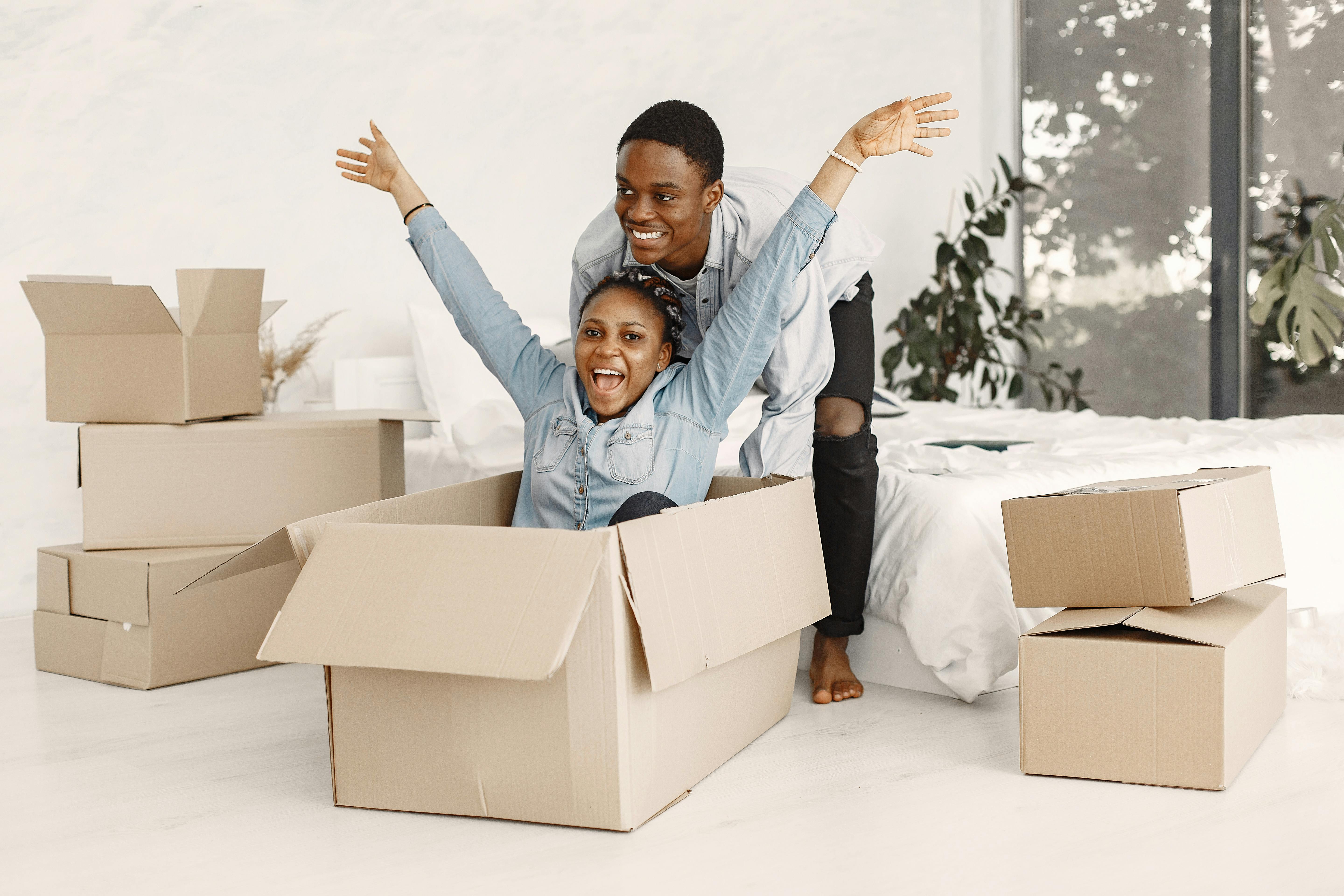 a man pushing a happy woman sitting in a cardboard box