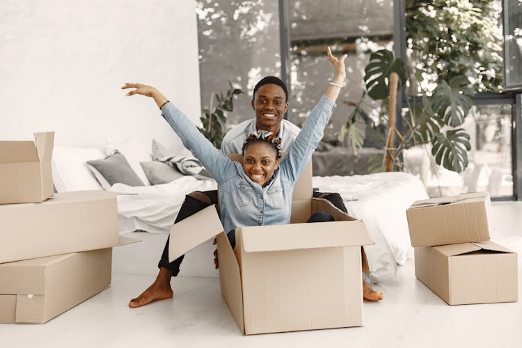 A Couple Playing With Cardboard Boxes Together