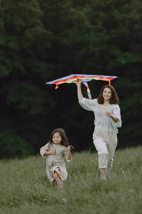 A Woman Holding a Kite while Playing with her Daughter