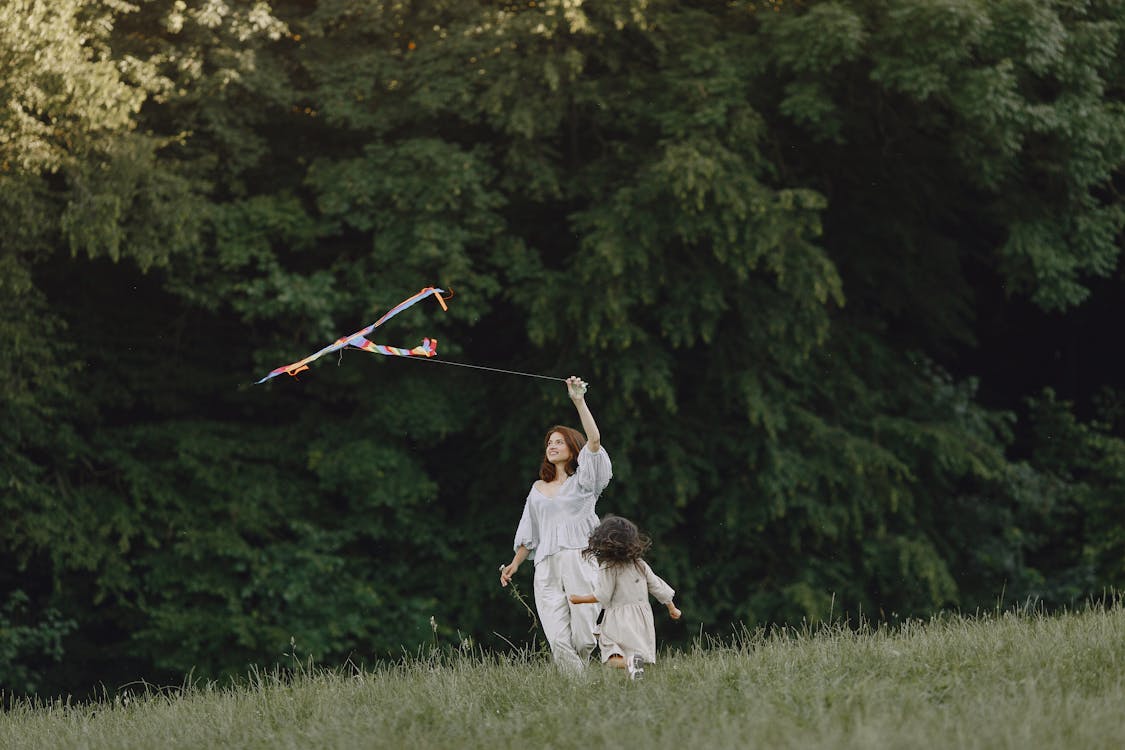 Free A Woman Flying a Kite with her Daughter at a Park Stock Photo