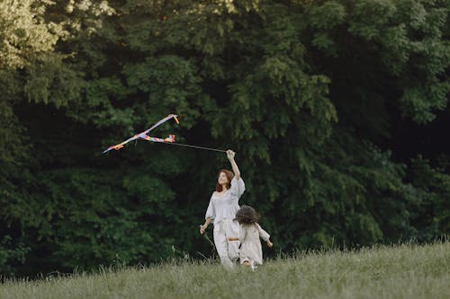 Free A Woman Flying a Kite with her Daughter at a Park Stock Photo