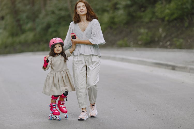 A Woman Teaching Her Daughter How To Rollerblade