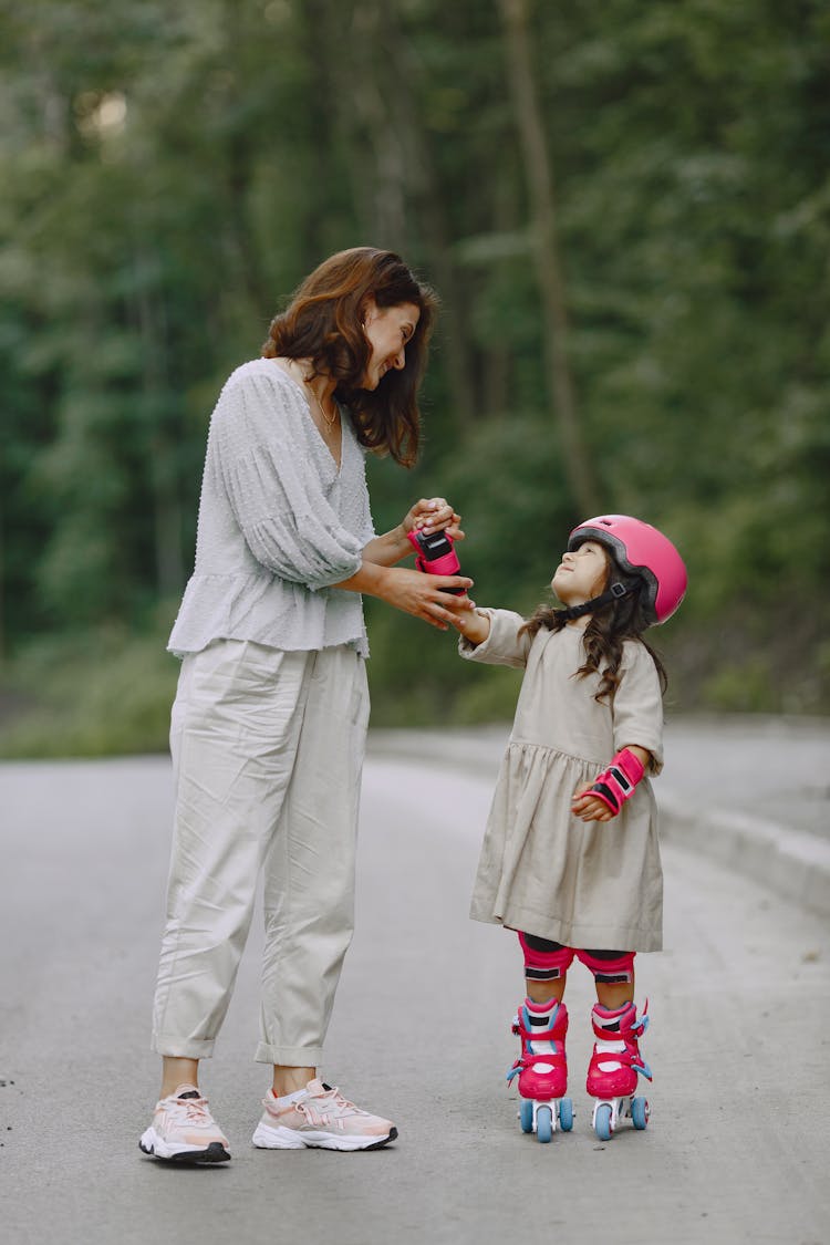 A Woman Teaching Her Daughter How To Rollerblade