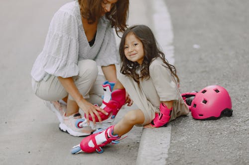 A Parent Helping her Daughter Wear Rollerblades