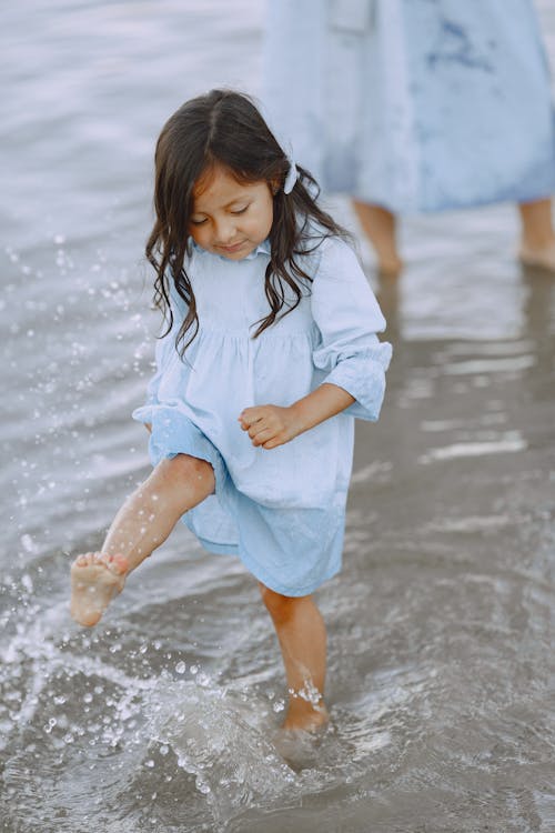 A Little Girl Making a Splash while Walking in Shallow Water