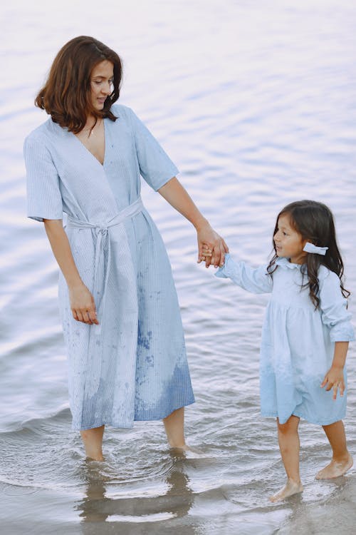 A Woman and her Daughter Holding Hands while Standing in Water