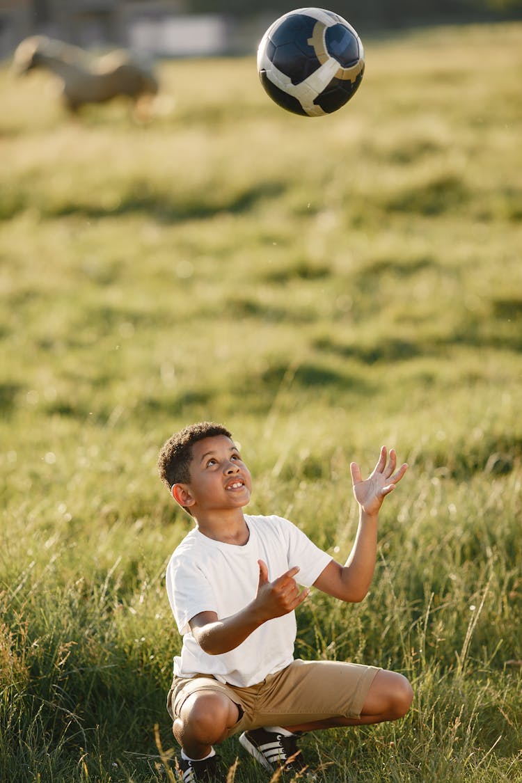 A Boy Tossing A Soccer Ball In The Air