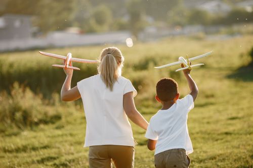 Free Joyful moment of mother and son playing with toy planes in a sunny field. Stock Photo
