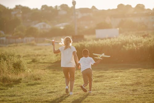 Free A Boy and Girl Running with Toy Planes Stock Photo