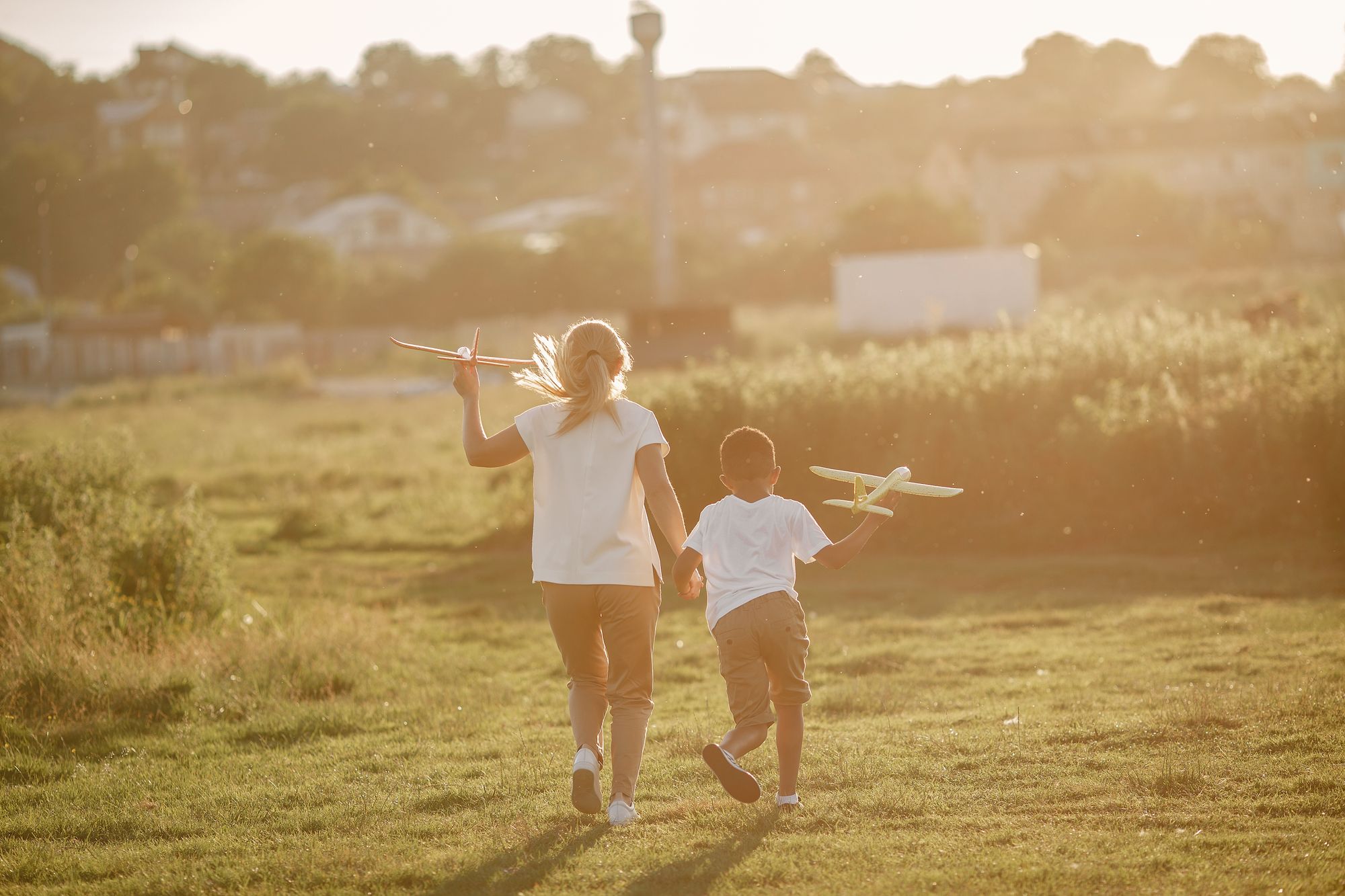 Madre e figli che camminano al tramonto con aerei giocattolo in mano