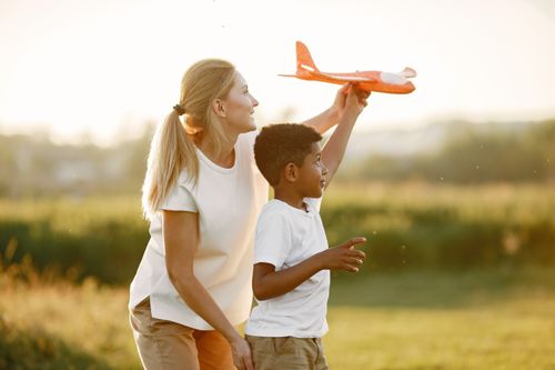 Free A young boy and woman enjoy playing with a toy plane in a sunny field. Stock Photo