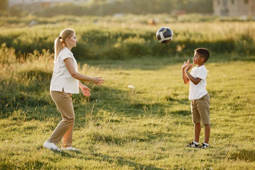 A mother and her young son enjoy playing soccer together on a sunny day outdoors.