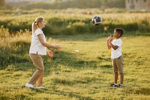 Free A mother and her young son enjoy playing soccer together on a sunny day outdoors. Stock Photo