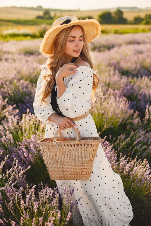 Free Stylish woman posing in a lavender field with a straw hat and dress, showcasing rural fashion. Stock Photo