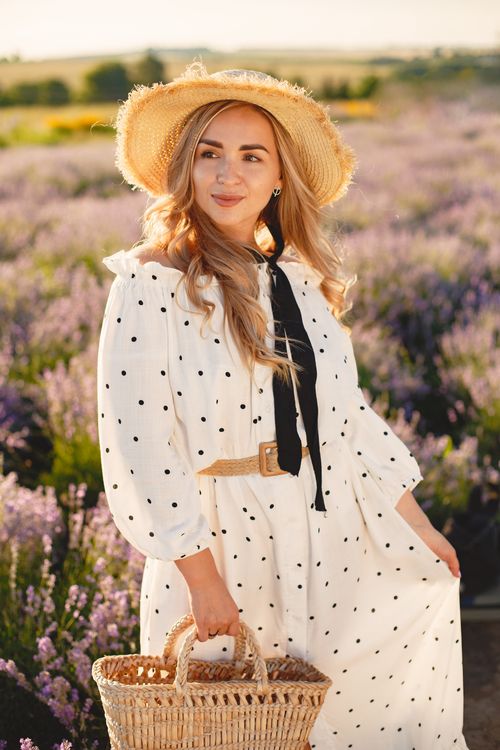 Free Beautiful woman in a polka dot dress with hat smiling in a vibrant lavender field. Stock Photo