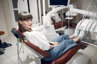 Woman in White Shirt and Blue Denim Jeans Sitting on Hospital Bed