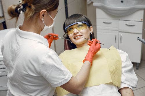 Free A woman sits smiling in a dental chair during a checkup. Stock Photo