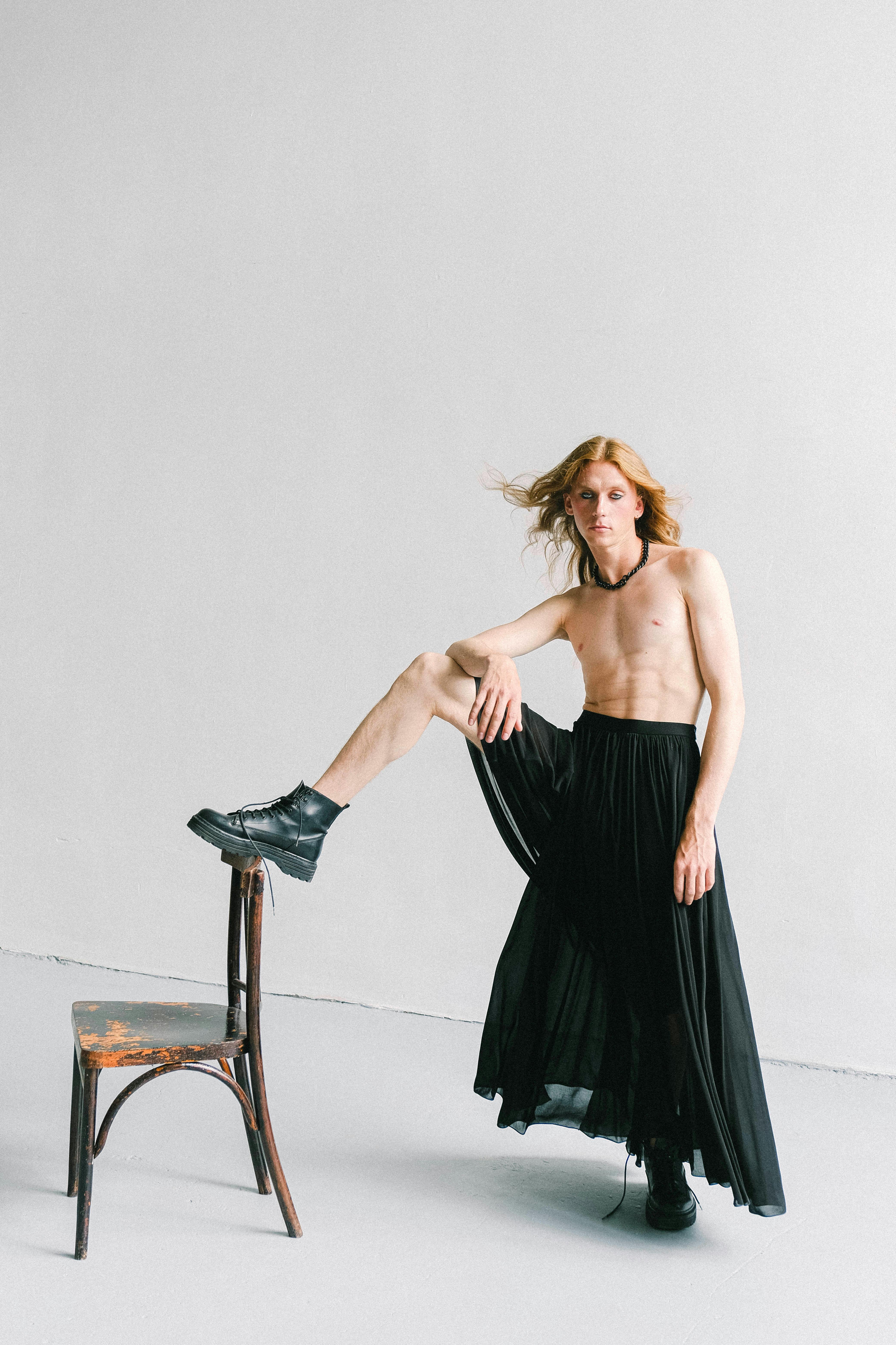 shirtless man in skirt in bright studio