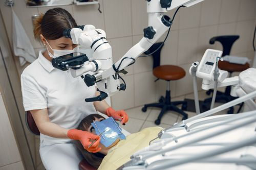 Free Dentist using advanced microscope for precise dental treatment in clinic. Stock Photo