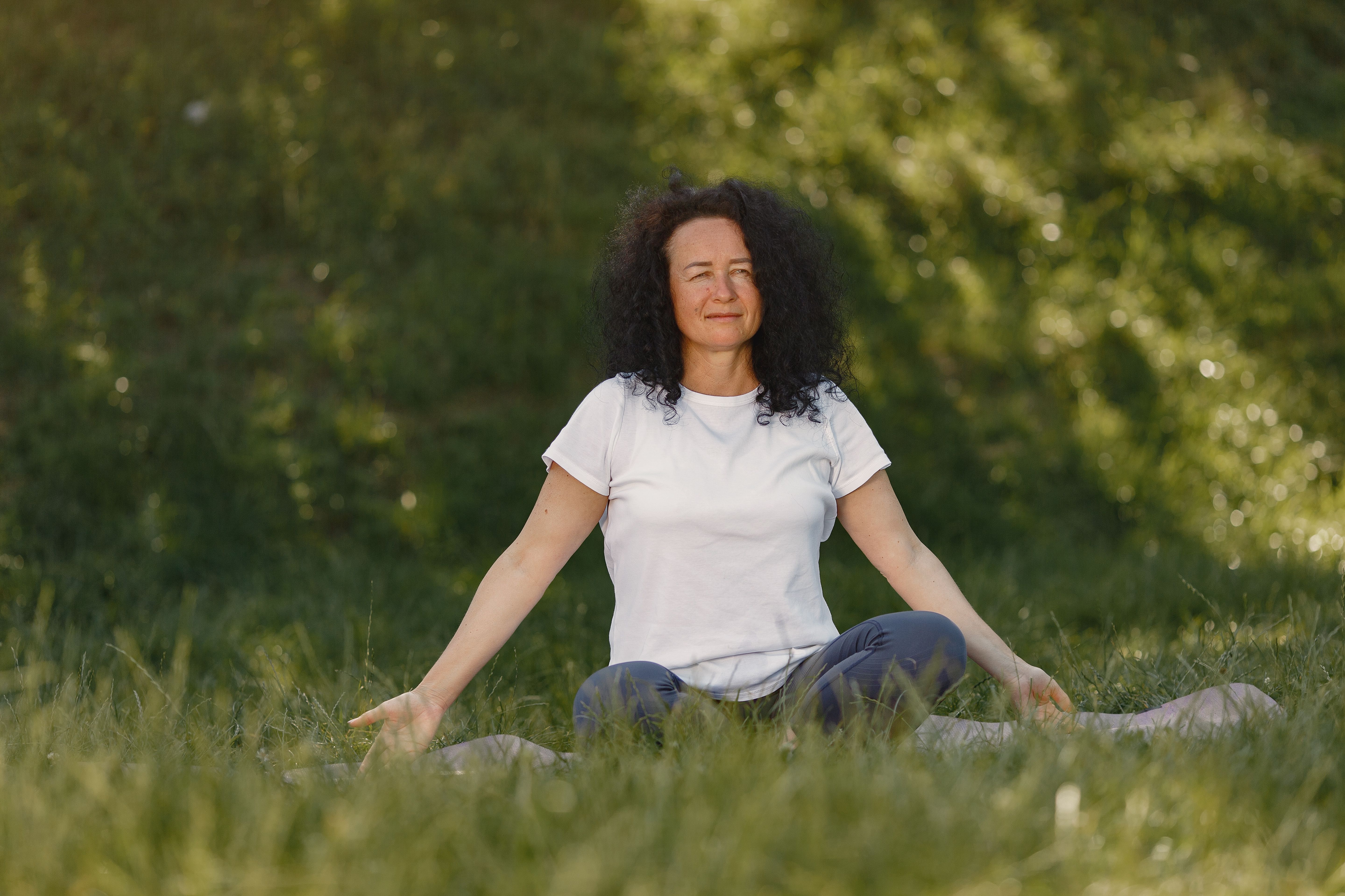 person smiling while meditating or sitting quietly in nature