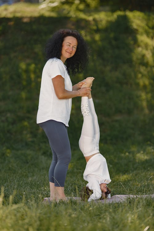 A Woman teaching her Daughter how to do a Headstand