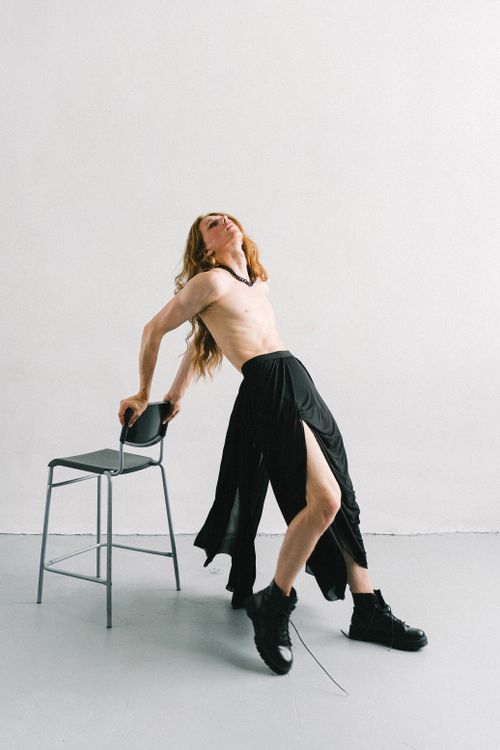 Free Shirtless model in a skirt and boots striking a pose in a studio setting. Stock Photo