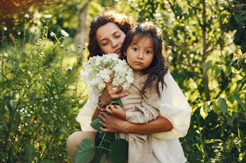 A Woman Holding a Bunch of Flowers with a Little Girl