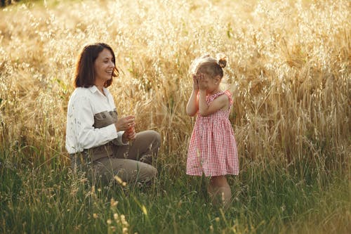 A Little Girl Playing Hide and Seek with her Mom in a Field
