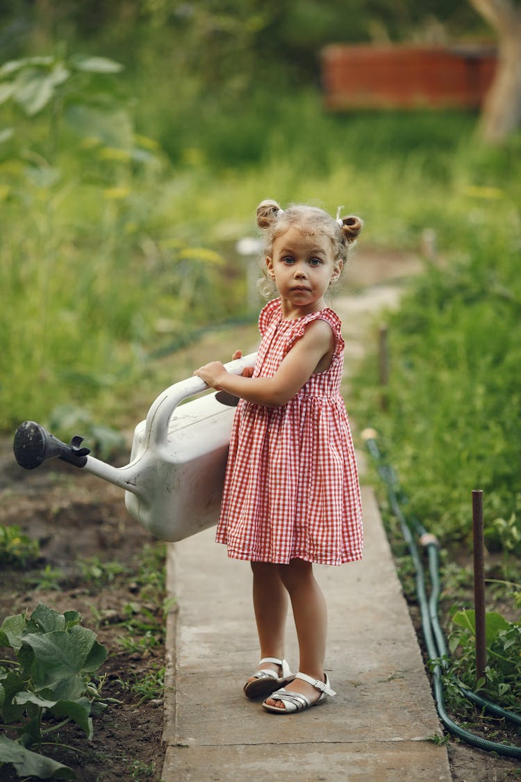 Child Holding Watering Can In Garden