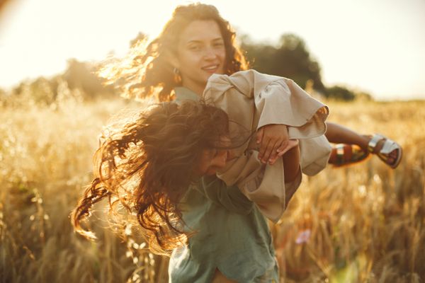 Mother spinning her daughter in a sunlit field