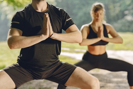 Man and woman practicing yoga outdoors, focusing on balance and mindfulness.