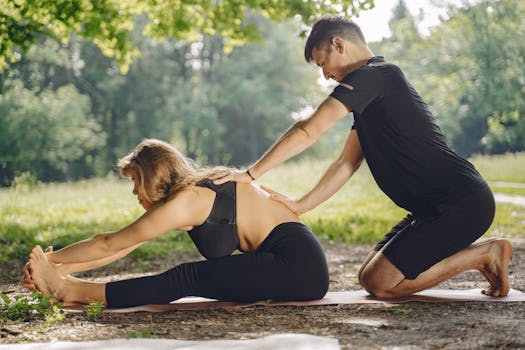 Two adults engaged in outdoor yoga, practicing partner stretching techniques in a serene natural setting.