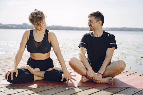 Couple Practising Yoga on a Pier and Smiling 