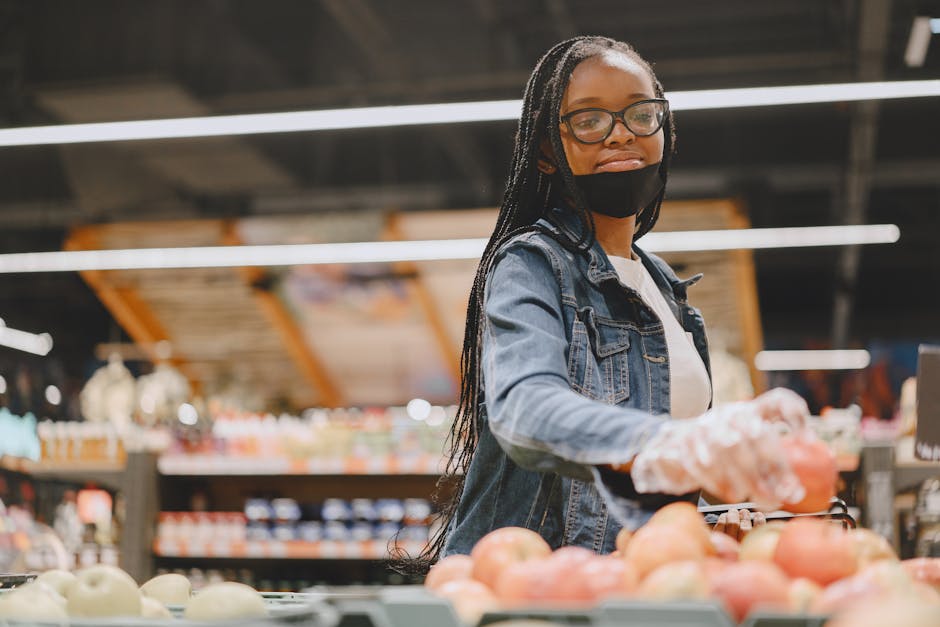Woman wearing mask and gloves shops for fresh fruit in a grocery store.