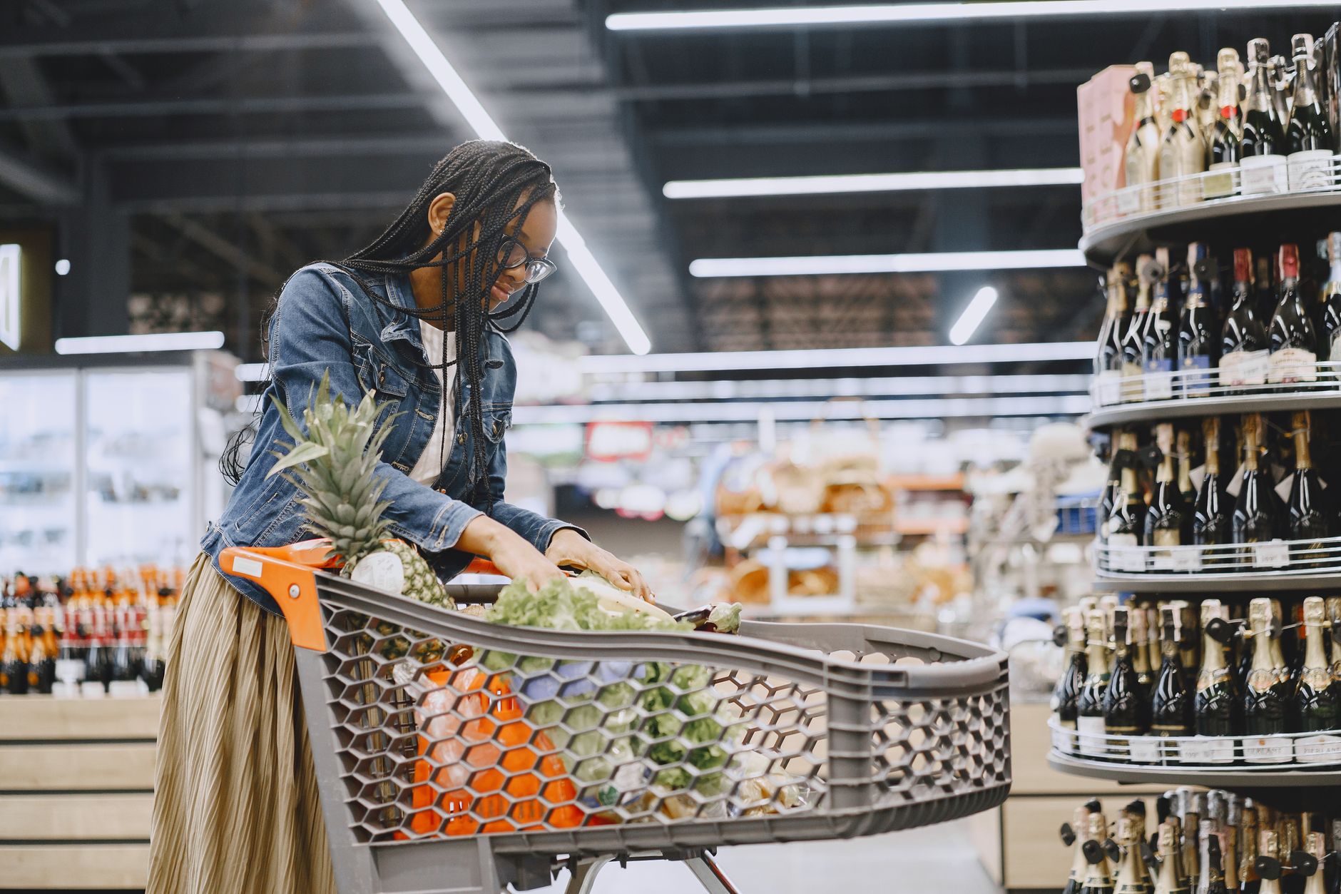 Almanya'daki bir süpermarkette uygun fiyatlı gıda alışverişini ve bütçe tasarrufunu temsil eden, taze sebze ve meyvelerle dolu bir alışveriş sepeti.