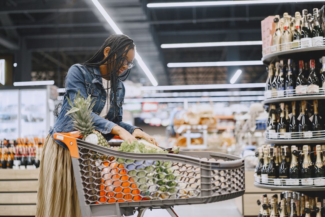 Shopper choosing fresh produce with a cart in a supermarket