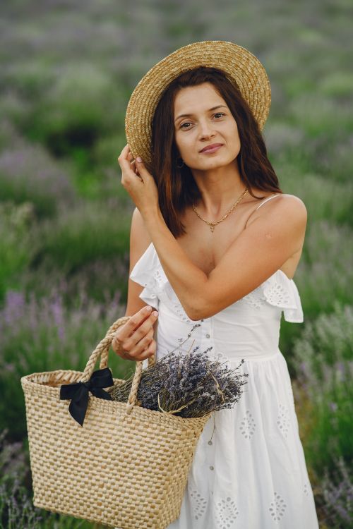 Free Elegant woman wearing a straw hat and white dress in a lavender field. Stock Photo