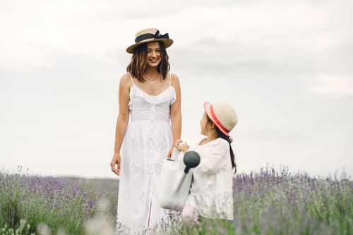 Free A joyful moment between mother and daughter wearing hats in a blooming lavender field during the daytime. Stock Photo